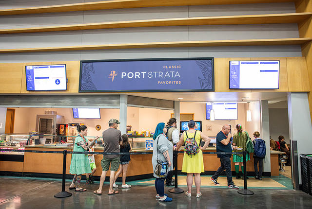 A dark blue sign that says "Port Strata" hangs over a small commissary inside an exhibit hall.